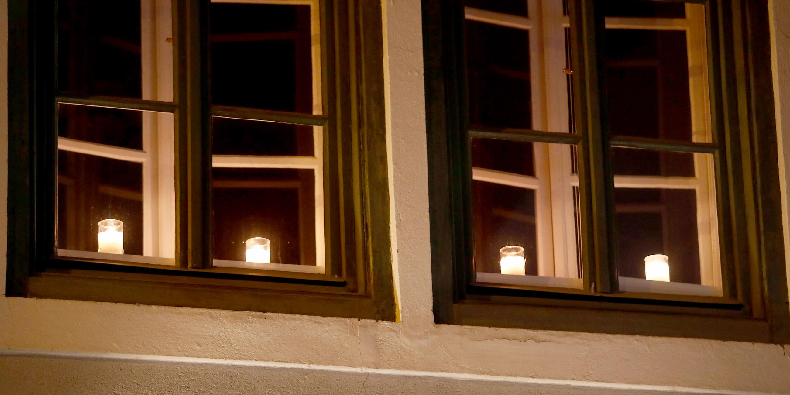 Österreich, Villach: Kerzen leuchten hinter einem Fenster als Zeichen der Trauer für die Opfer des Messeranschlags.