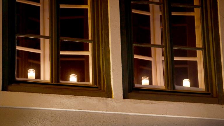 Österreich, Villach: Kerzen leuchten hinter einem Fenster als Zeichen der Trauer für die Opfer des Messeranschlags.