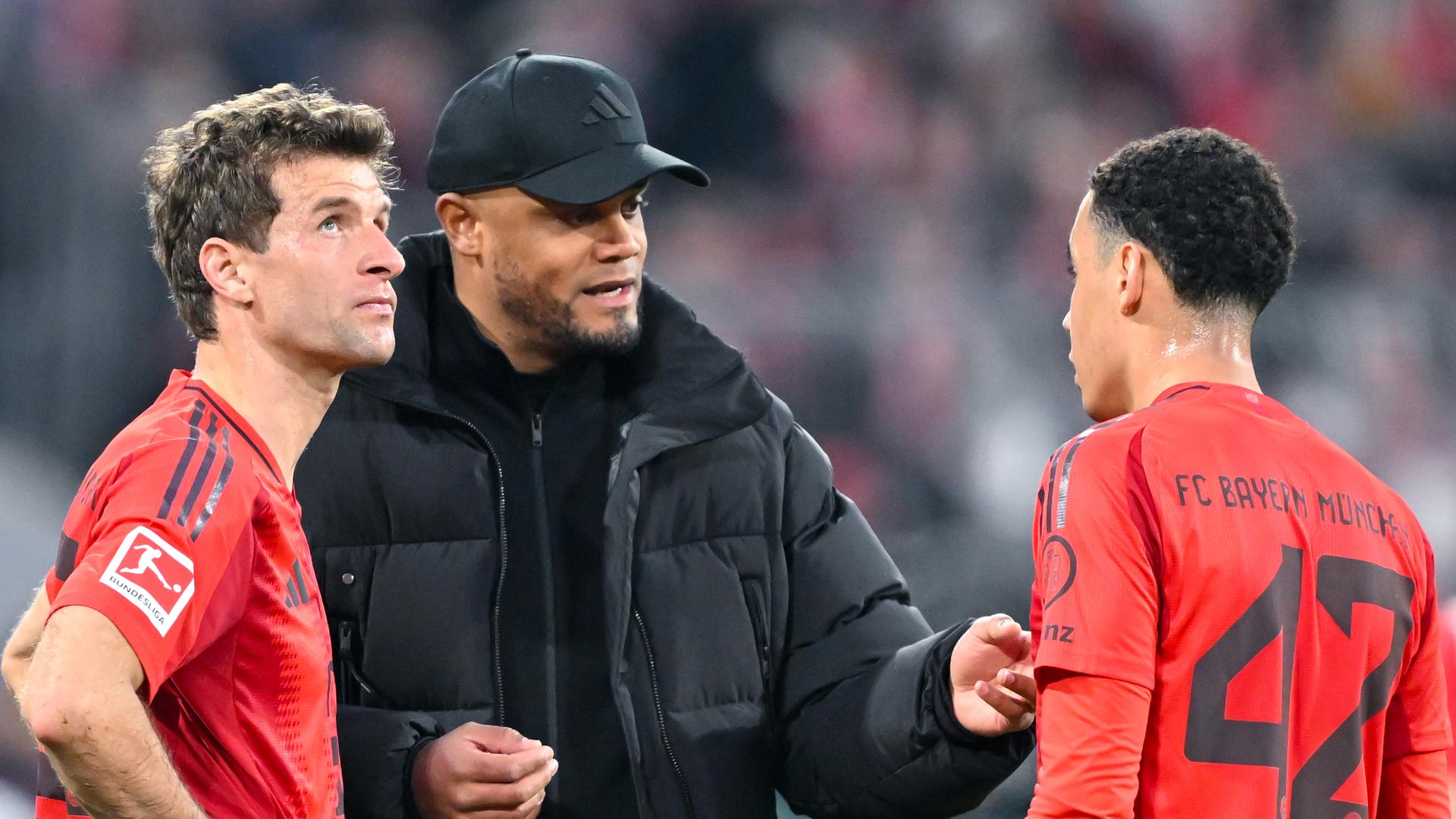 Bayern Münchens Trainer Vincent Kompany spricht mit Thomas Müller (l) und Jamal Musiala.