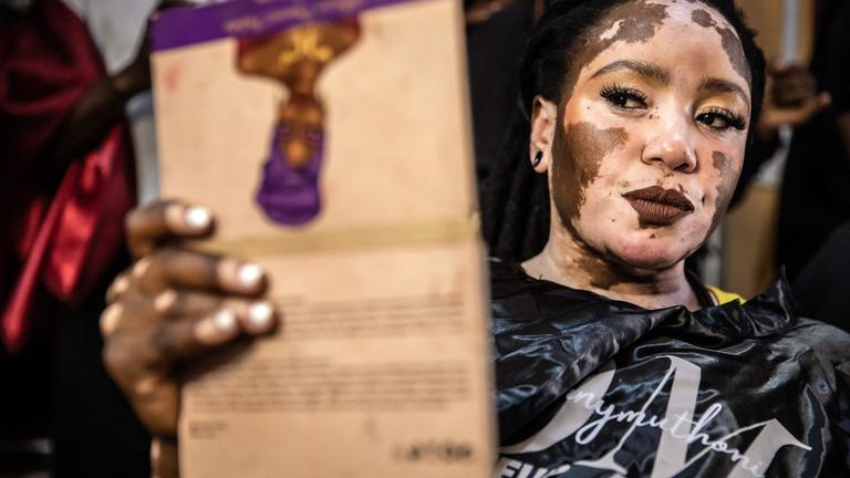 Das Vitiligo-Model Julie Nasuju betrachtet sich in einem tragbaren Spiegel, nachdem sie sich geschminkt hat.