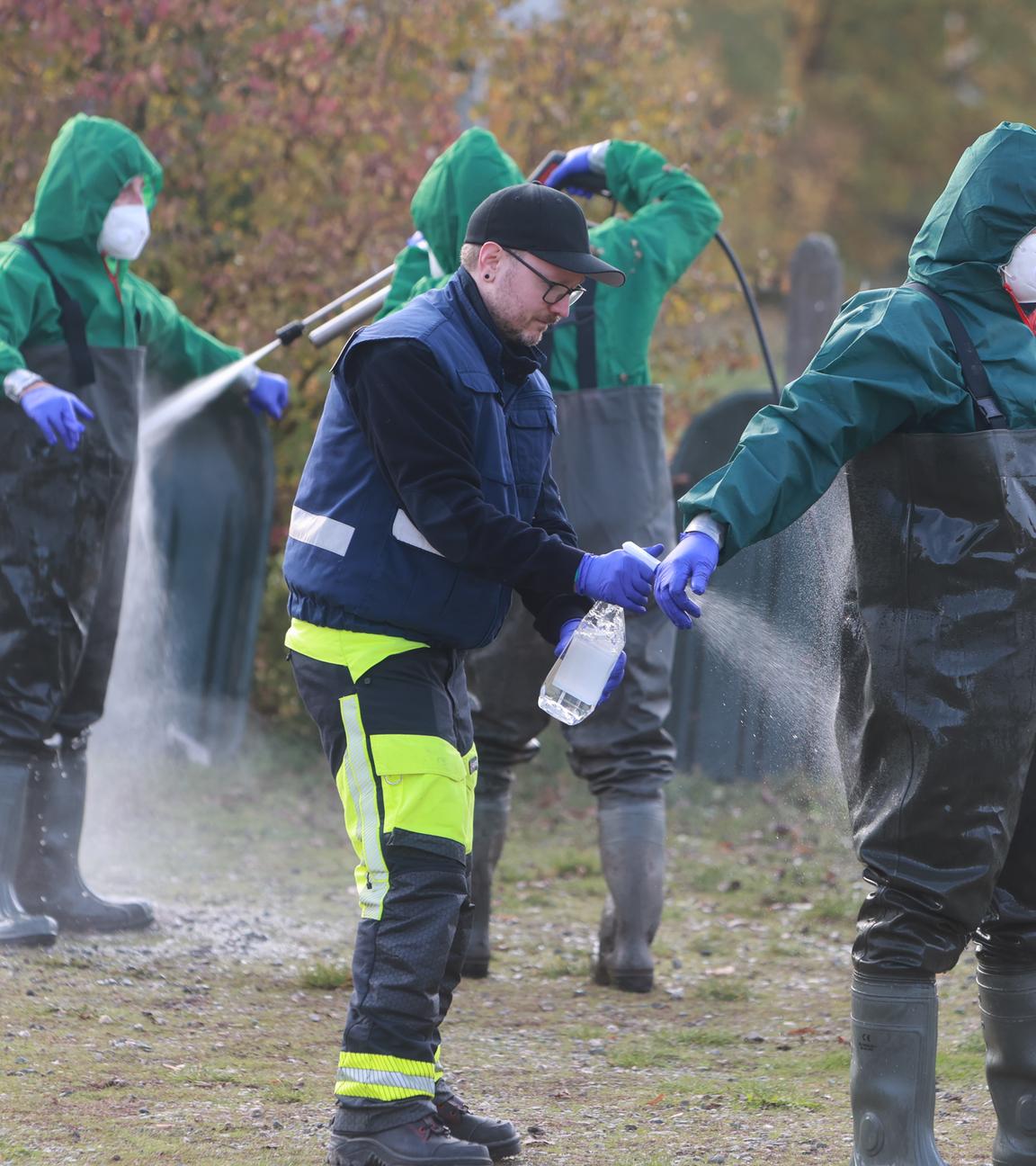 Einsatzkräfte der Feuerwehr werden nach der Suche nach infizierten oder verendeten Kranichen desinfiziert. 