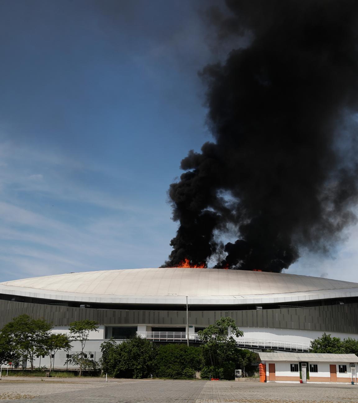 Brasilien, Rio de Janeiro: Rauch steigt vom Dach des Velodroms im Olympiapark auf, während die Feuerwehr im Einsatz ist.
