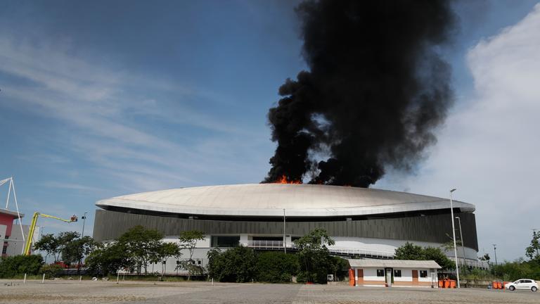 Brasilien, Rio de Janeiro: Rauch steigt vom Dach des Velodroms im Olympiapark auf, während die Feuerwehr im Einsatz ist.