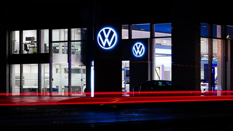Niedersachsen, Hannover: Fahrzeuge fahren am frühen Morgen vor einem Volkswagen-Autohaus entlang