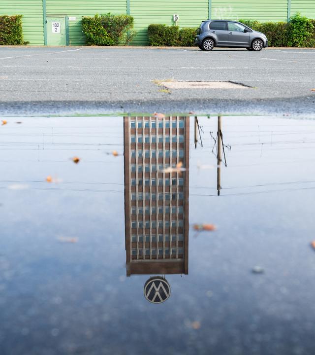 Symbolbild:  Das Markenhochhaus am VW-Stammwerk spiegelt sich in einer Pfütze. 