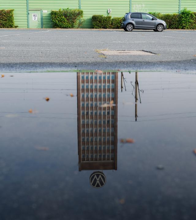 Symbolbild:  Das Markenhochhaus am VW-Stammwerk spiegelt sich in einer Pfütze. 