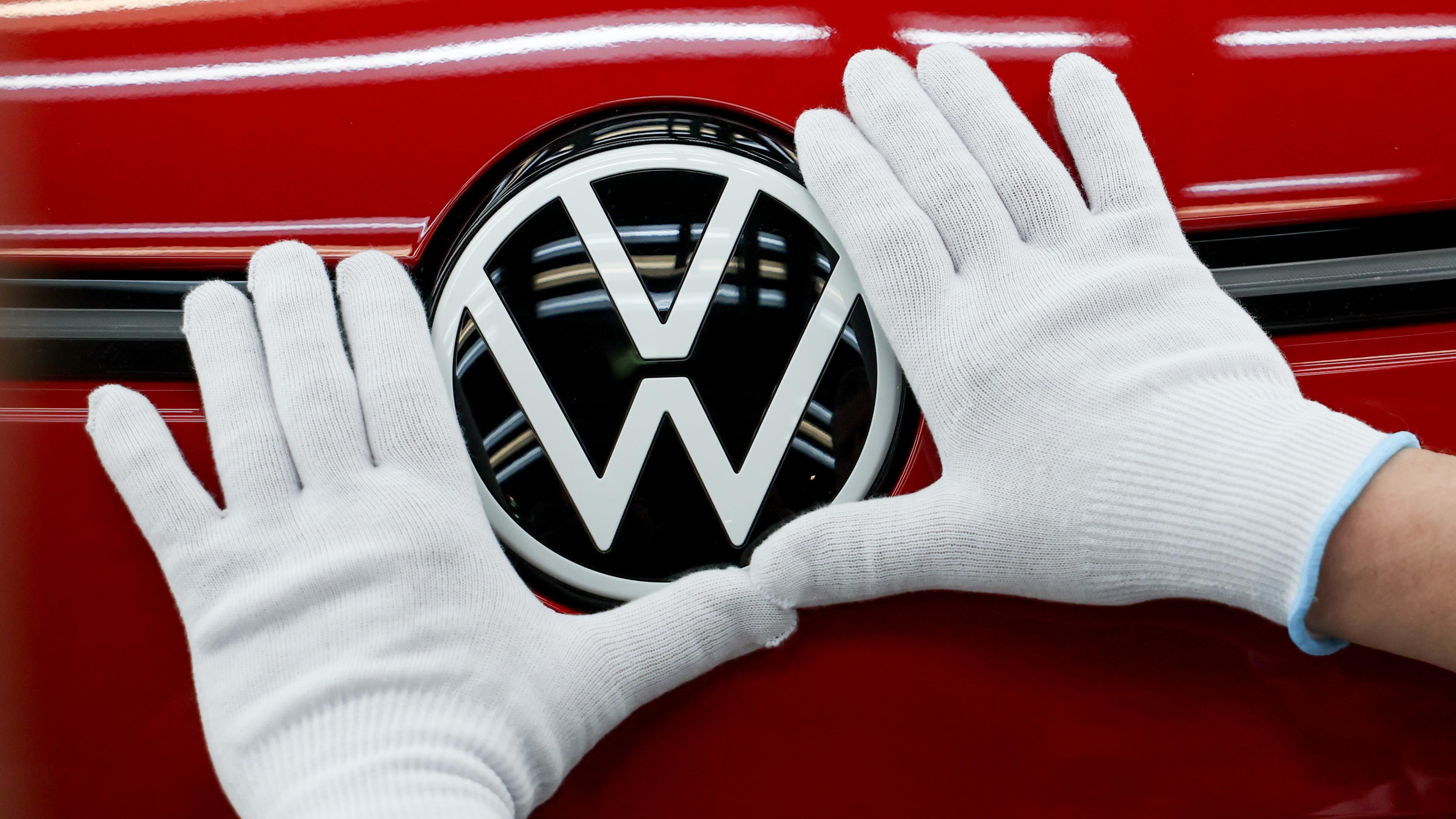 Die Hände eines Mitarbeiters berühren ein Volkswagen Logo