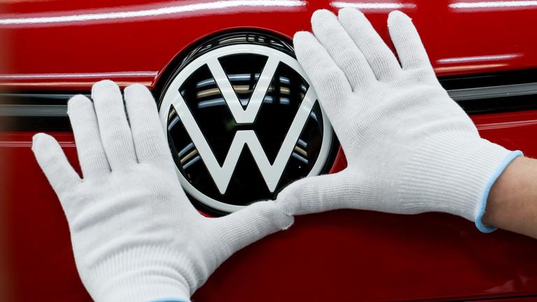 Die Hände eines Mitarbeiters berühren ein Volkswagen Logo