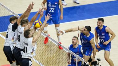 In der Volleyballpartie spielt das serbische Nationalteam den Ball über das Netz und zwingt damit das deutsche Nationalteam zur Abwehr