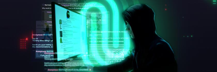 Mann mit dunklem Kapuzen-Shirt sitzt vor einem Computer