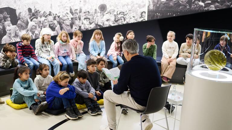 Manuel Neukirchner, Direktor des Deutschen Fußballmuseums, liesst im Deutschen Fußballmuseum Schulkindern vor.