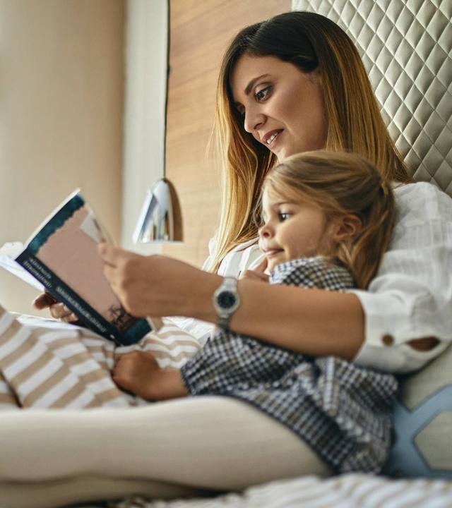 Mutter und Tochter lesen ein Buch im Bett (Symbolfoto)
