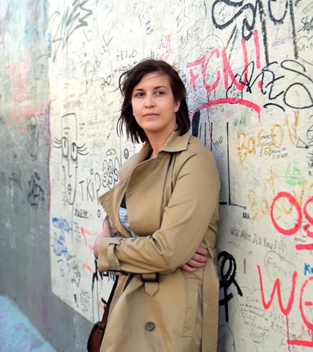 Junge Frau lehnt an Mauer
