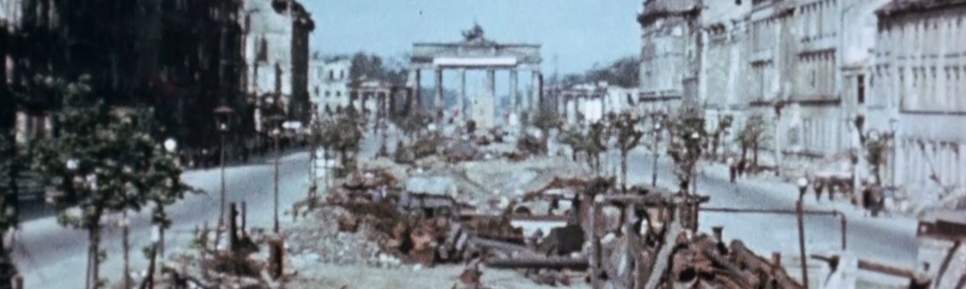 Das zerstörte Berlin 1945. Man sieht das Brandenburger Tor und eine kaputte Straße.