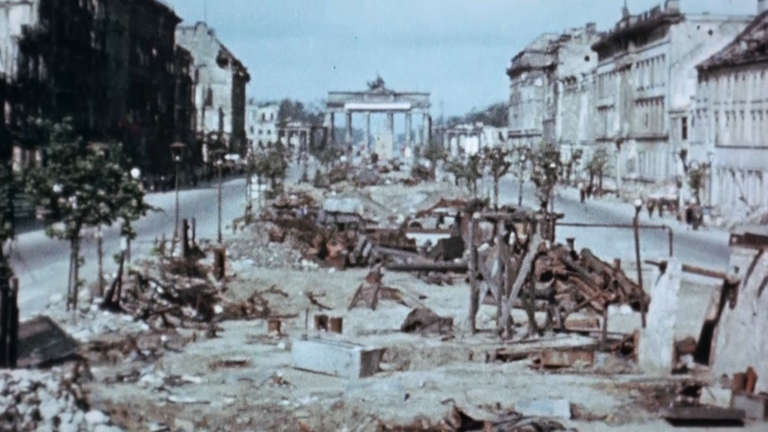 Das zerstörte Berlin 1945. Man sieht das Brandenburger Tor und eine kaputte Straße.