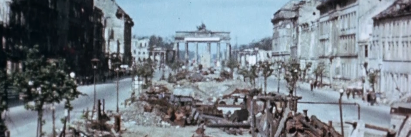Das zerstörte Berlin 1945. Man sieht das Brandenburger Tor und eine kaputte Straße.