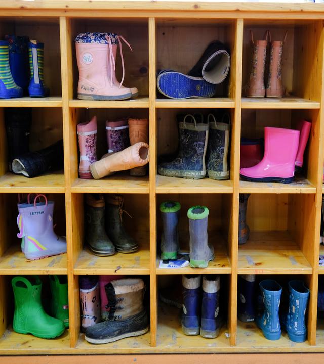 Kinderstiefel stehen in einem Kindergarten in einem Regal.