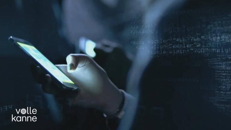 Person hält ein Handy in der Hand (dunkle Aufnahme).