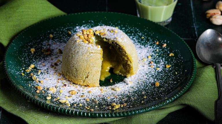 Ein Kuchen mit Füllung auf einem grünen Teller mit Puderzucker.