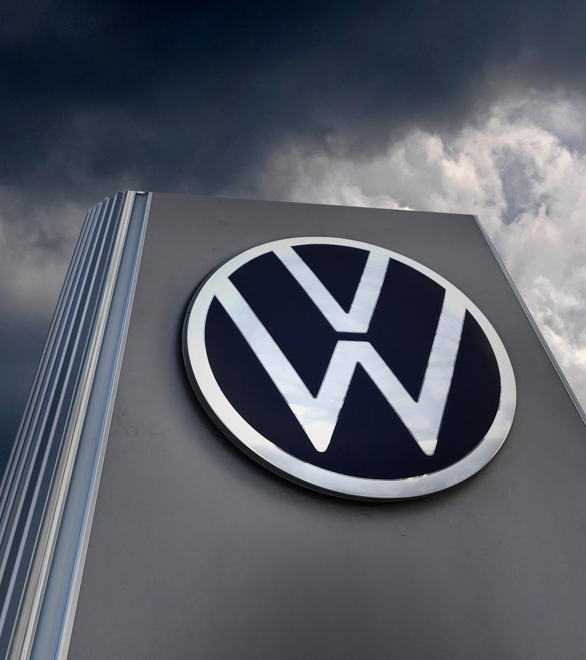 VW-Schild vor dunklen Wolken.