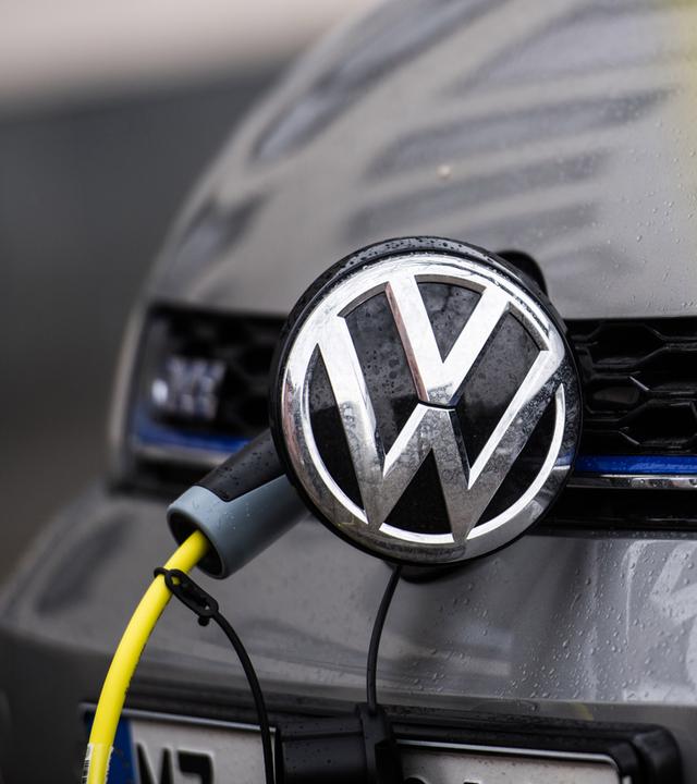 Ein VW-Auto wird mit einem Kabel geladen. 