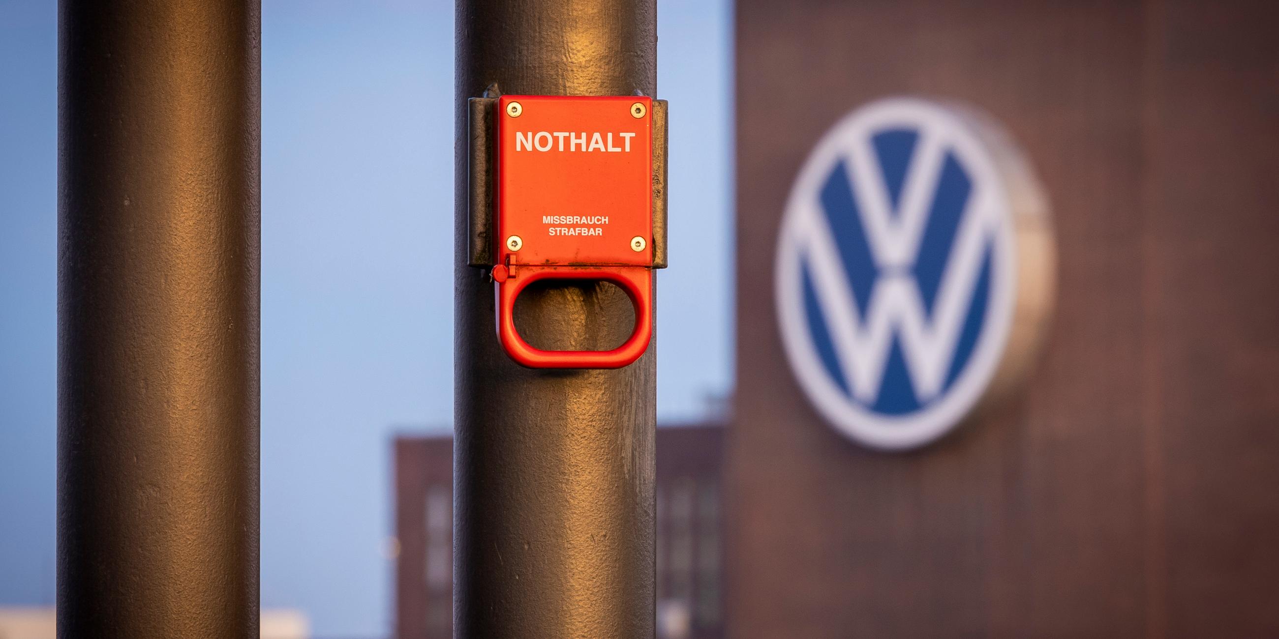 Niedersachsen, Wolfsburg: Ein Schalter mit der Aufschrift "Nothalt" ist am Morgen am Bahnhof vor einem Logo am Volkswagen-Stammwerk zu sehen.