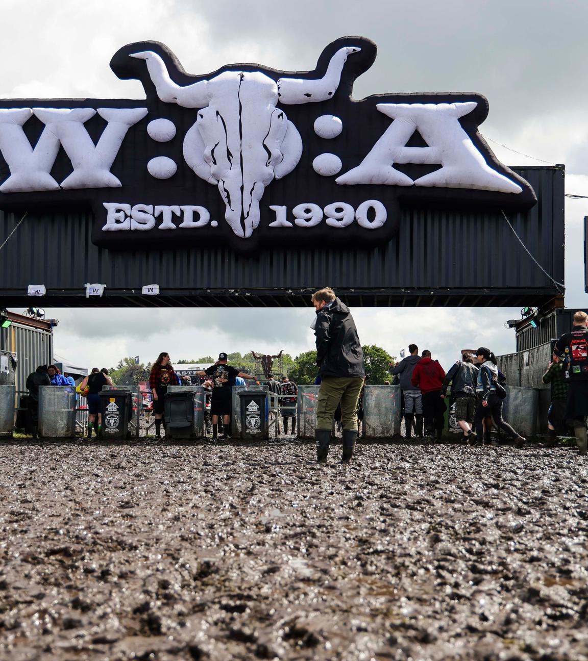 Wacken: Metal-Fans gehen über das matschige Festivalgelände des Wacken Open Air..