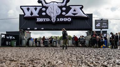 Wacken: Metal-Fans gehen über das matschige Festivalgelände des Wacken Open Air..