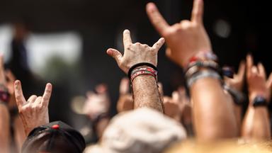 Fans beim Wacken Open Air recken die Hände mit gestrecktem Zeigefinger und kleinem Finger hoch zum Metal-Gruß.