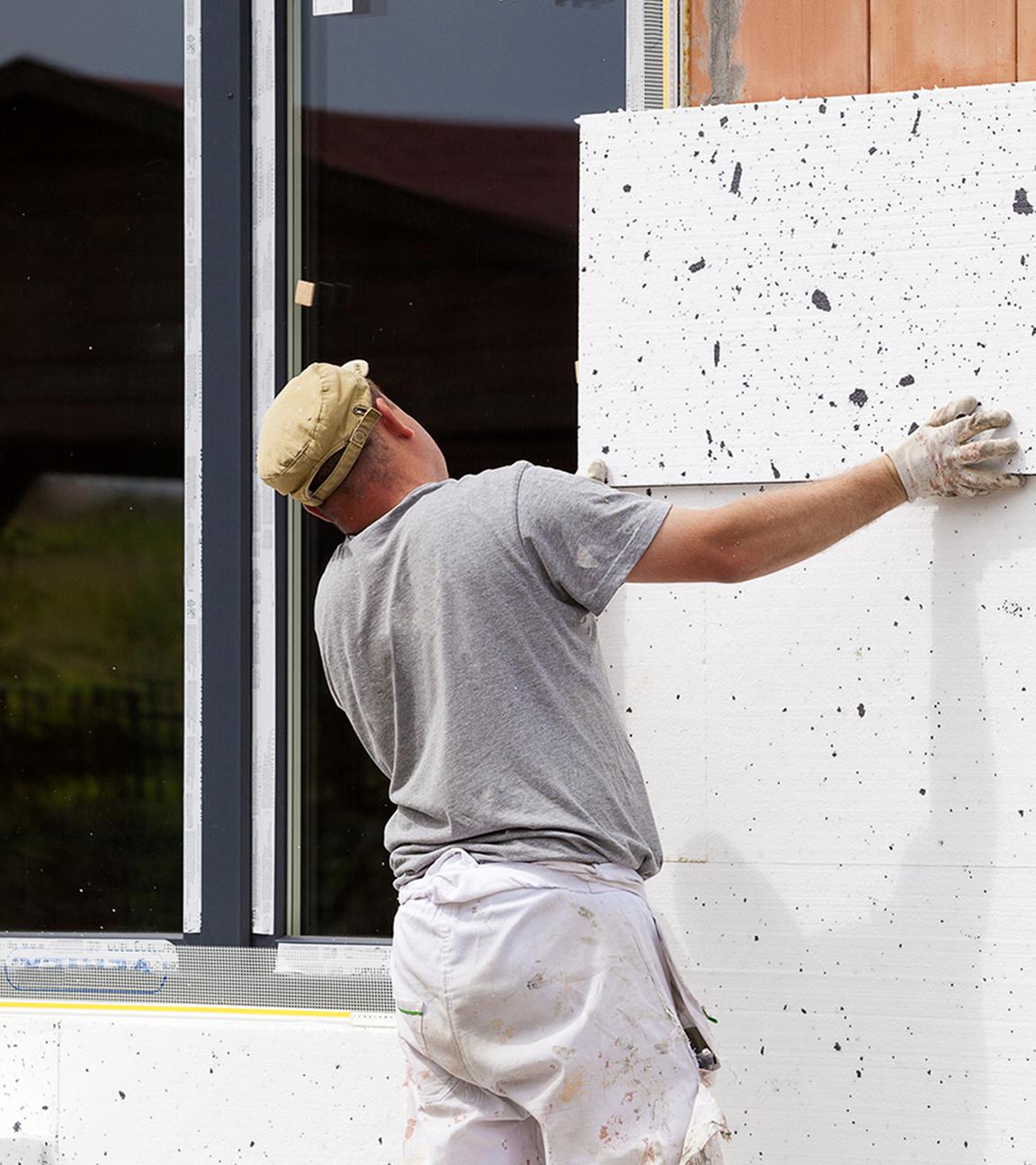 Handwerker bringt Außendämmung an Fassade an