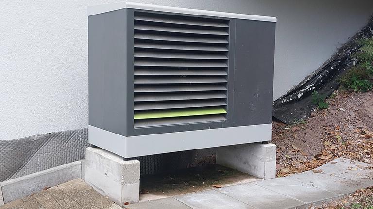Wärmepumpe steht vor einer Aussenwand