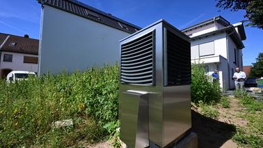 Baden-Württemberg, Plankstadt: Vor einem neu gebauten Wohngebäude ist im Garten eine Wärmepumpe zum Heizen des Gebäudes in Betrieb.