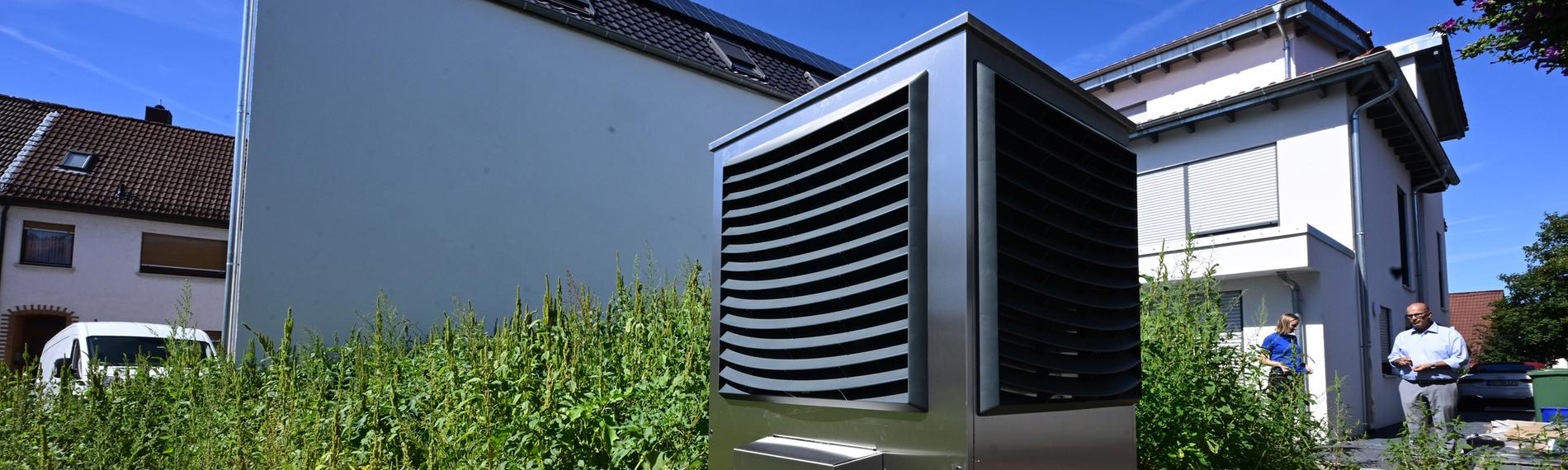 Eine neue Wärmepumpe steht vor einem Wohnhaus.