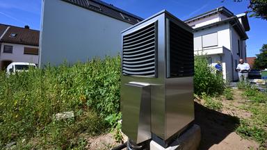 Eine neue Wärmepumpe steht vor einem Wohnhaus.