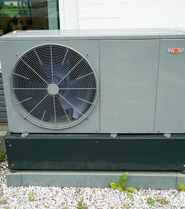 Eine Wärmepumpe der Firma Wolf steht vor einem Haus.
