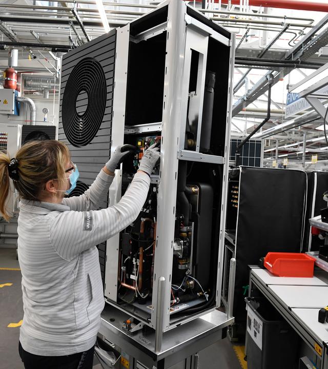 Eine Mitarbeiterin der Firma Vaillant montiert eine Wärmepumpe.