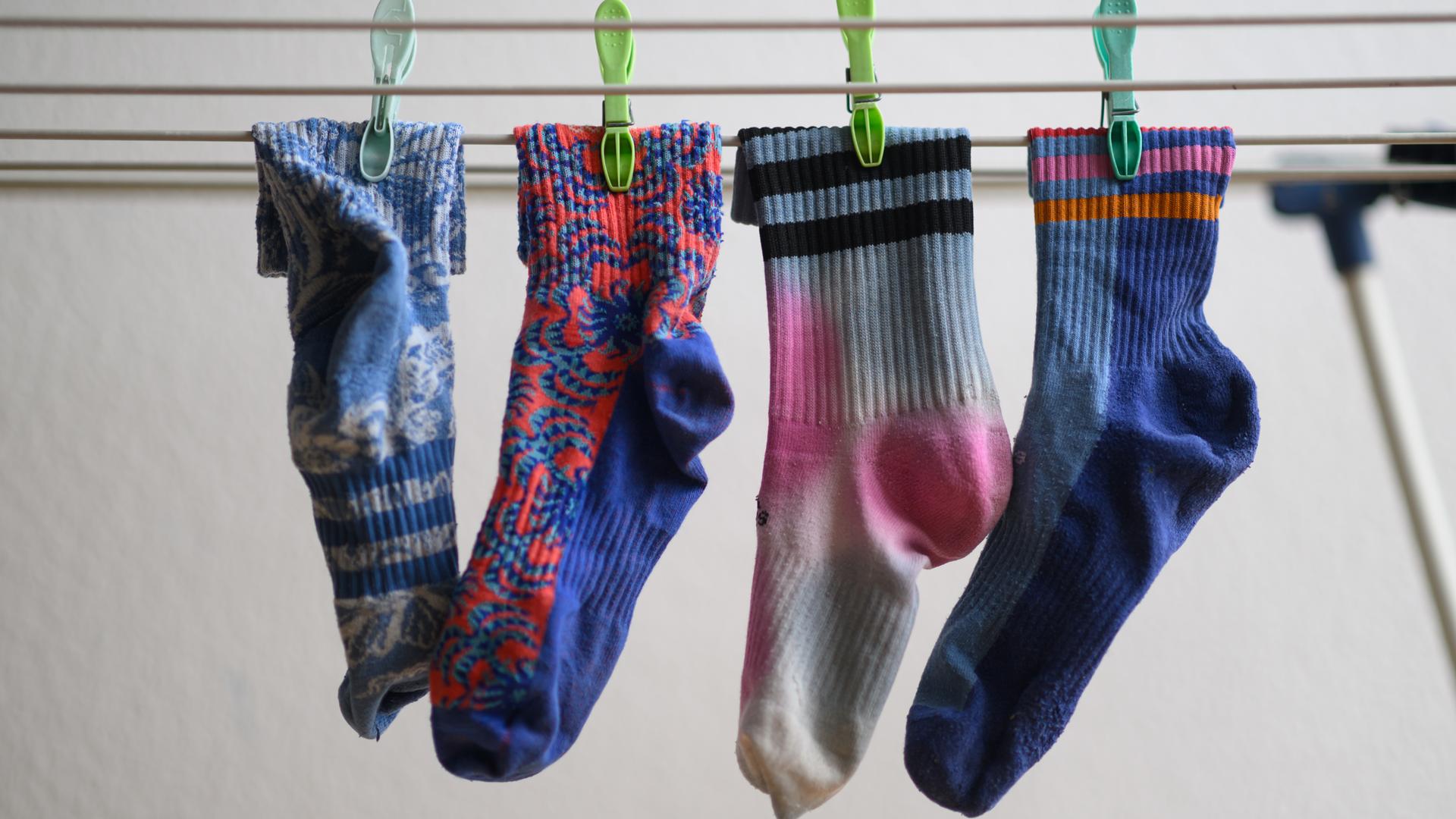 Bunte Socken hängen an einem Wäscheständer.