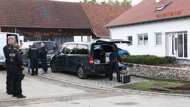 Polizisten und Kriminaltechniker stehen vor einem Tatort.