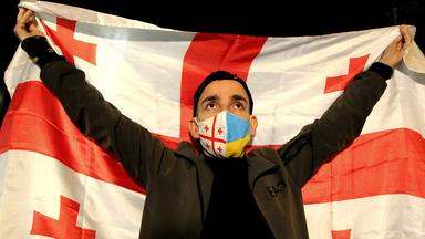 Ein Mann hält eine Flagge von Georgien