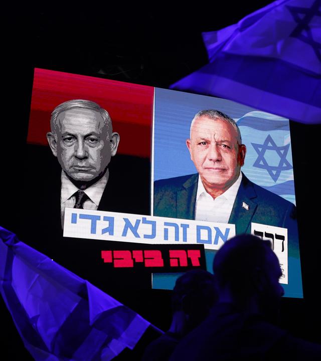 Bei einer Wahlkampfveranstaltung in der Dizengoff-Straße schwenken Menschen israelische Flaggen unter einem Transparent, auf dem Gadi Eisenkot (M) und der israelische Ministerpräsident Benjamin Netanjahu abgebildet sind. 