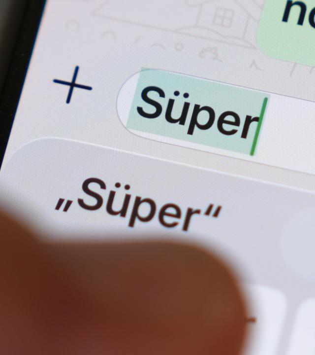 Das Wort Süper ist auf dem Display eines Smartphones in einem Chatverlauf zu lesen. 