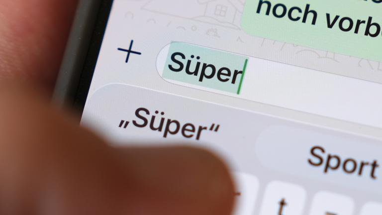 Das Wort Süper ist auf dem Display eines Smartphones in einem Chatverlauf zu lesen. 