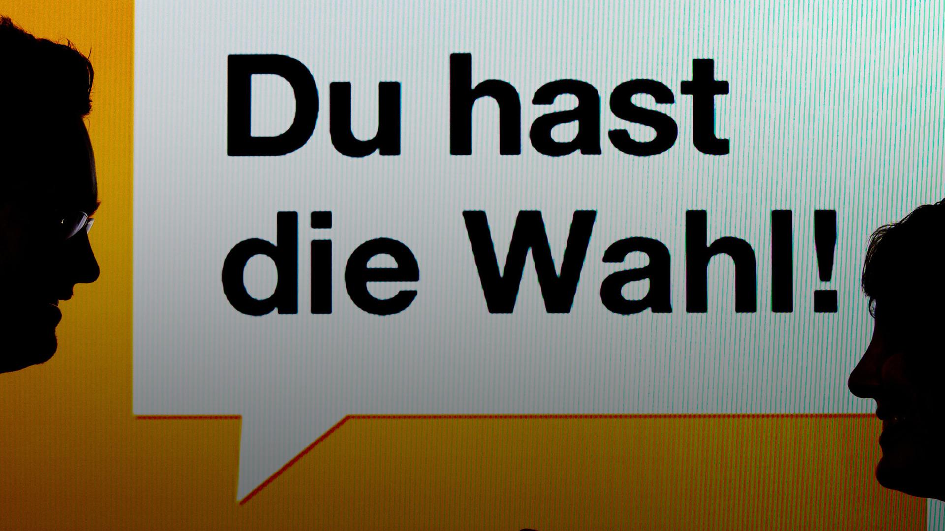 Zwei junge Leute stehen am 22.08.2013 in München vor einen Bildschirm mit der Aufschrift "Du hast die Wahl! - Wahl-O-Mat". 