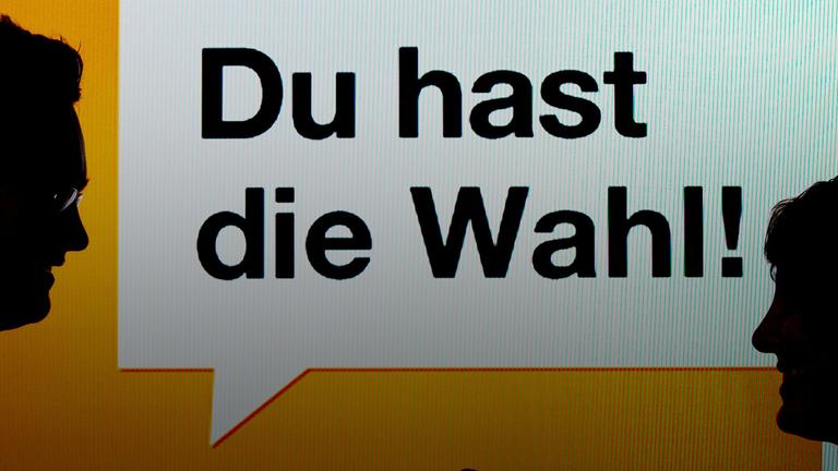 Zwei junge Leute stehen am 22.08.2013 in München vor einen Bildschirm mit der Aufschrift "Du hast die Wahl! - Wahl-O-Mat". 