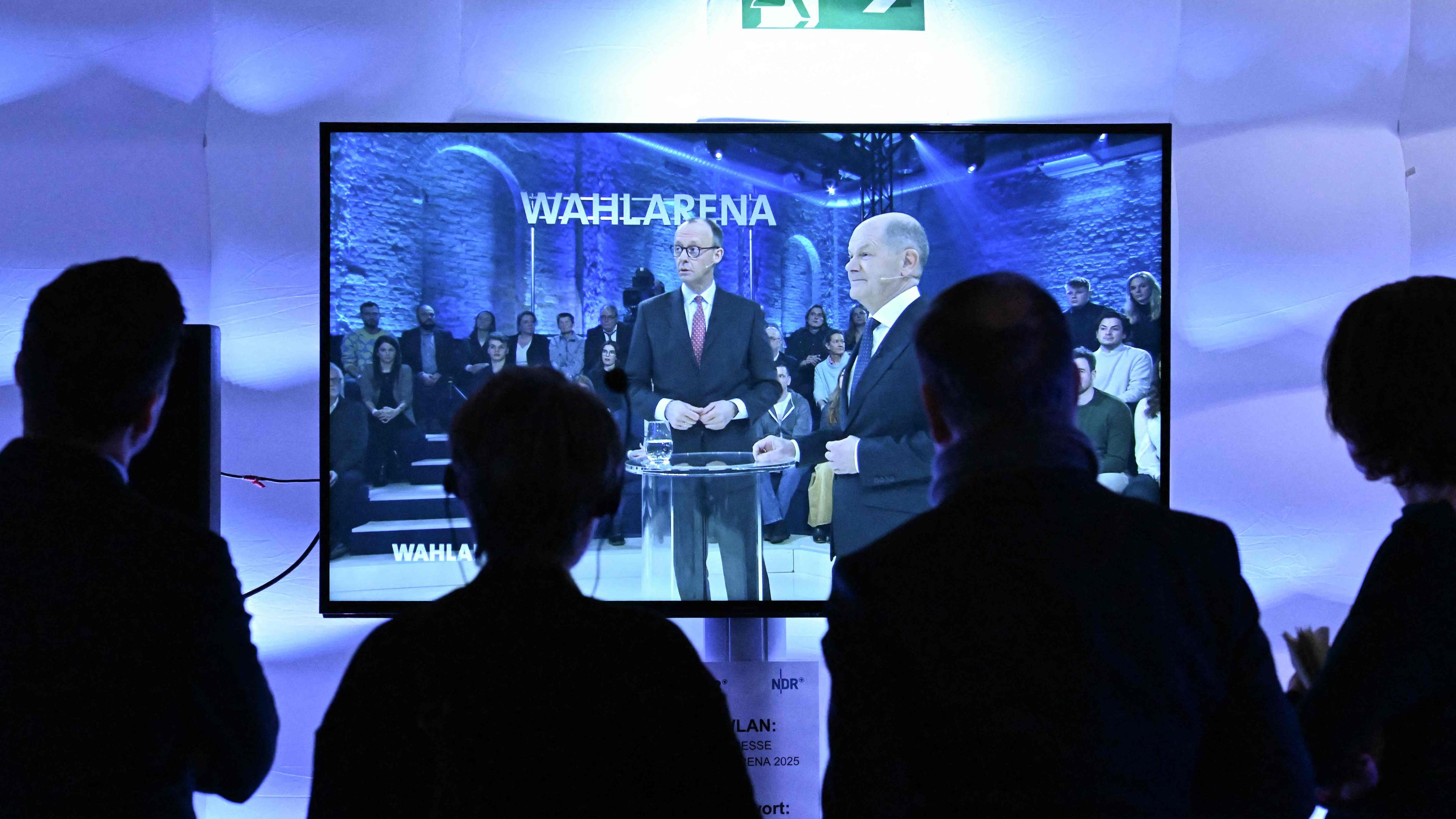 Die Kanzlerkandidaten Olaf Scholz (SPD) und Friedrich Merz sind auf einem Fernsehbildschirm im Studio der ARD-Wahlarena zu sehen.