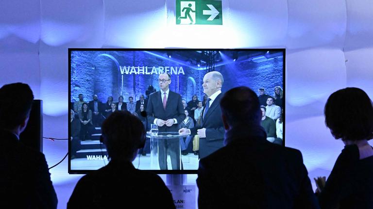 Die Kanzlerkandidaten Olaf Scholz (SPD) und Friedrich Merz sind auf einem Fernsehbildschirm im Studio der ARD-Wahlarena zu sehen.