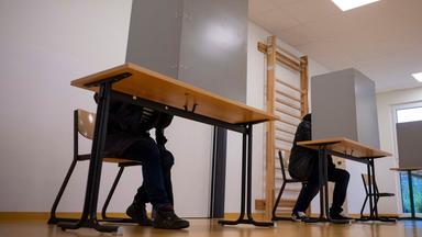 Drei Wahlkabinen mit zwei Menschen in Kabinen