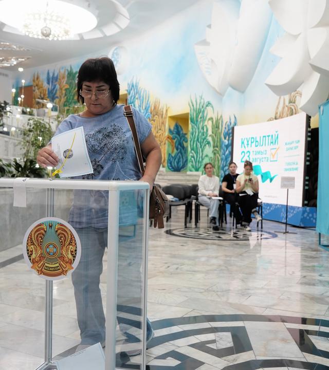 Eine Frau gibt am Sonntag, dem 23. August 2026, bei vorgezogenen Parlamentswahlen in Almaty, Kasachstan, in einem Wahllokal ihre Stimme ab. 