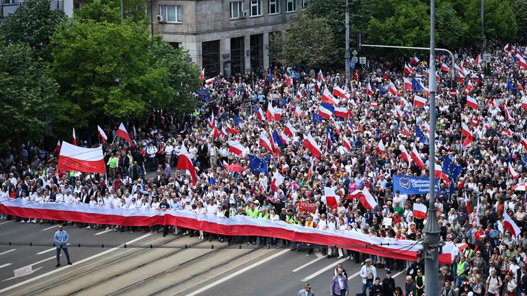 Anhänger des polnischen Präsidentschaftskandidaten Rafal Trzaskowski, der auch Bürgermeister von Warschau und Mitglied der regierenden zentristischen Partei Bürgerkoalition ist, schwenken bei einer Wahlkampfkundgebung in Warschau am 25. Mai 2025, eine Woche vor der zweiten Runde der Präsidentschaftswahlen, die Flaggen Polens und der Europäischen Union (EU), während sie durch die Straßen gehen.