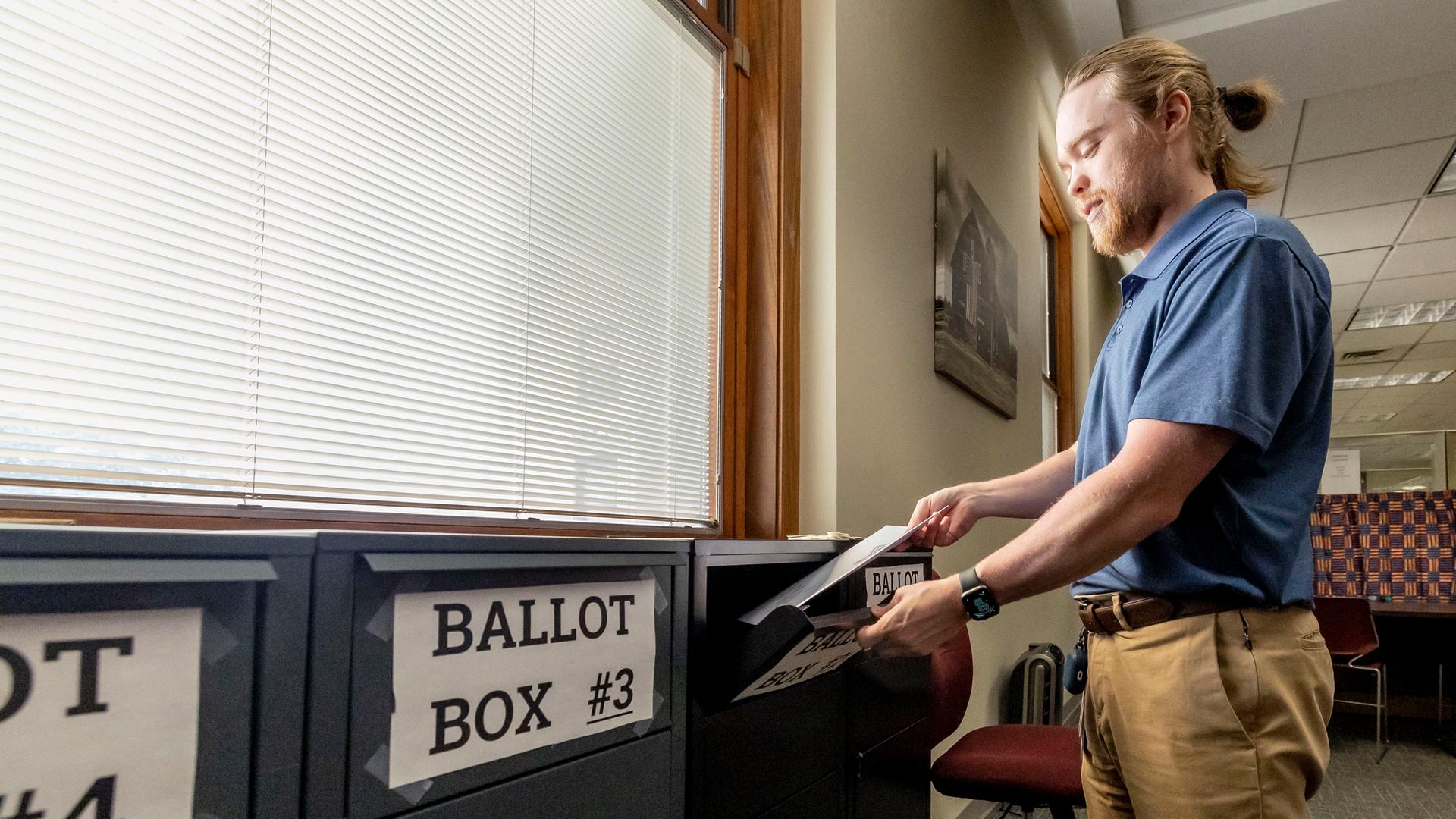 Es ist ein Mann zu sehen, wie er seinen Wahl-Zettel einwirft.